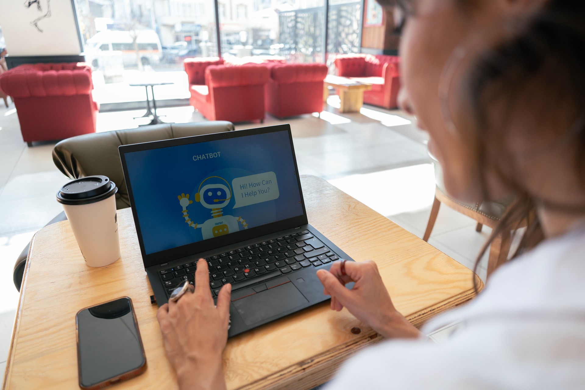 Businesswoman using chatbot while working on laptop in cafe